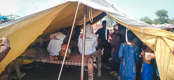 Operatori di MSF e persone colpite dall'alluvione sotto una tenda di rifugio allestita al nostro team, nel Balochistan