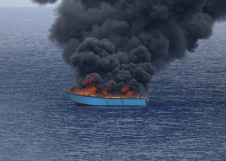 Una barca di legno a fuoco dopo essere stata intecettata dalla guardia costiera libica nel Mediterraneo